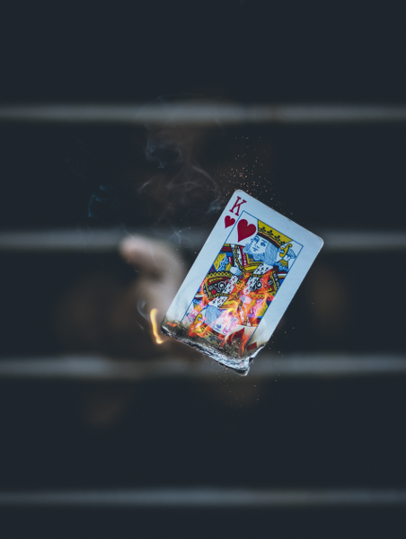 man-throwing-burning-kings-of-card
